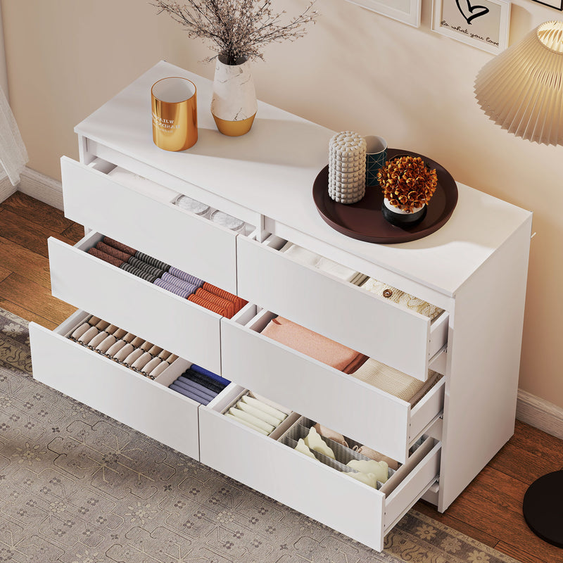 White dresser with open drawers containing various items in a room setting.