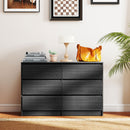 Black dresser with decorative items in a room with framed pictures on the wall.