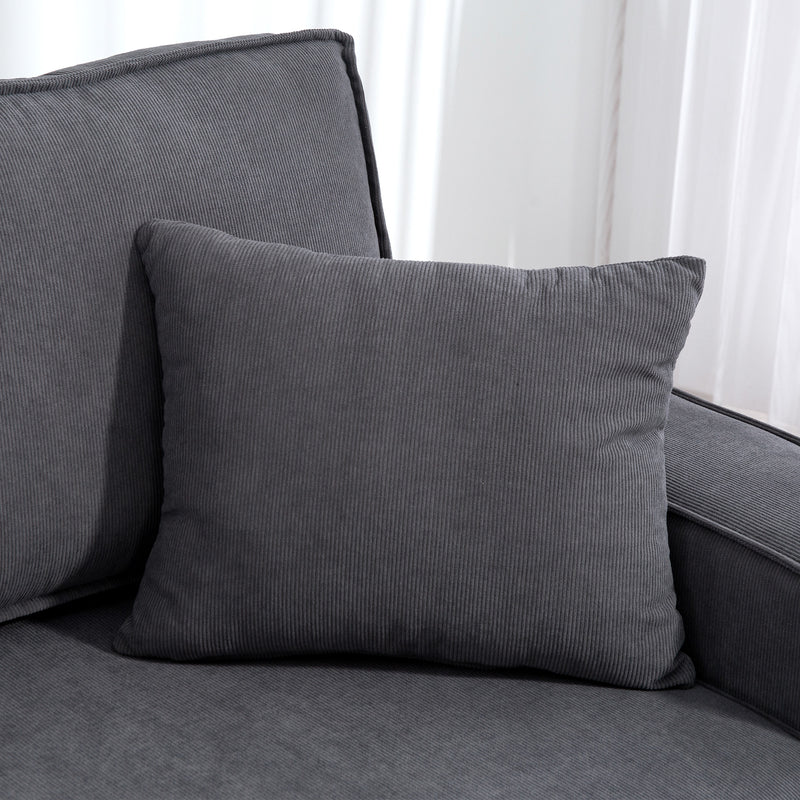 Gray cushion on a gray sofa with white curtains in the background